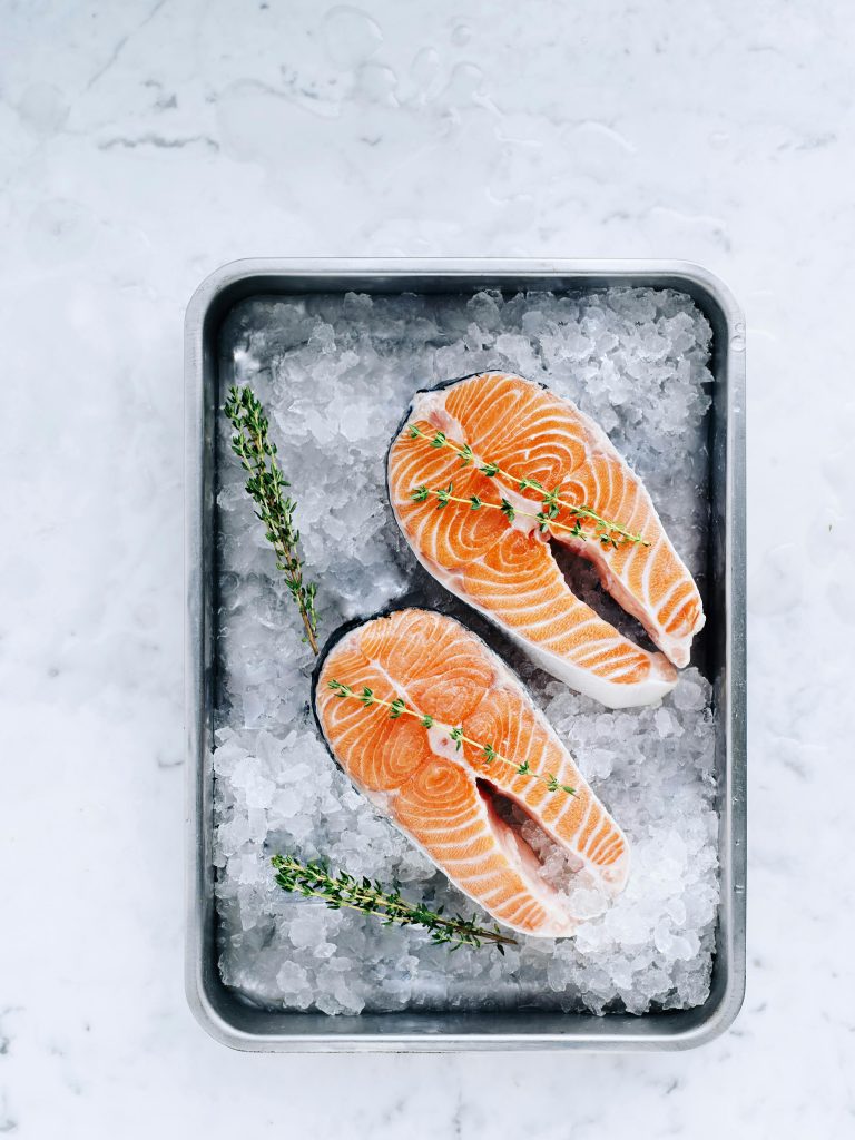Closeup of raw salmon fillets with thyme on ice, perfect for gourmet meals.