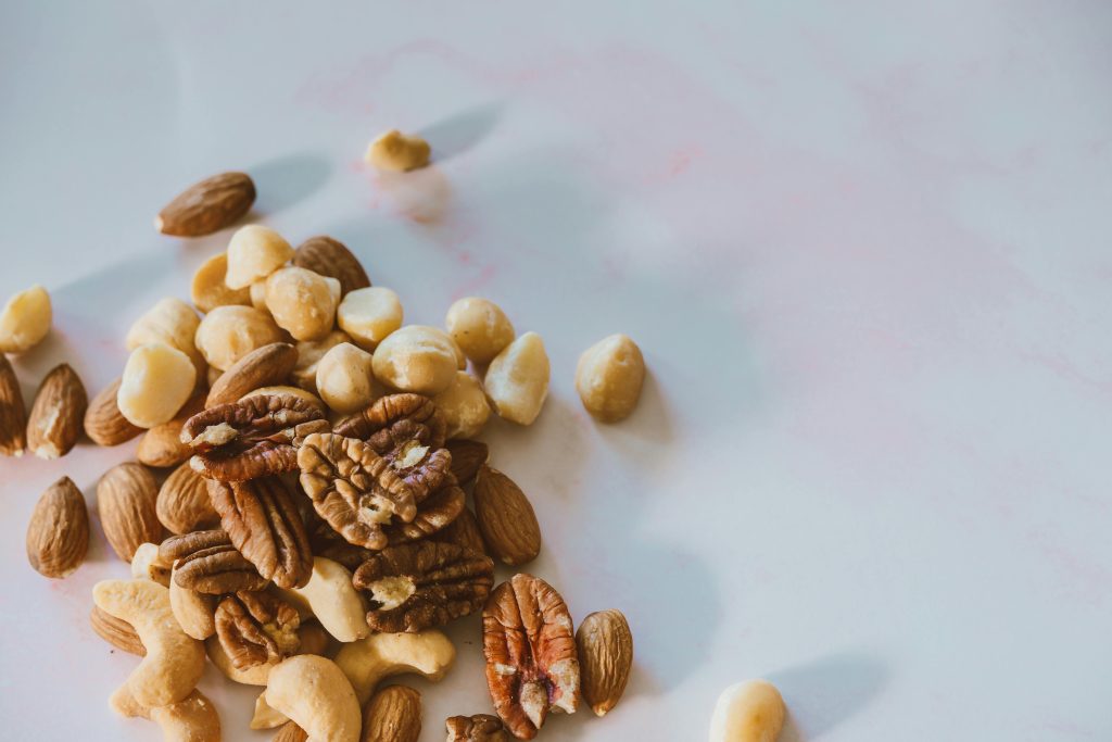 A close-up of various nuts like almonds, pecans, and macadamia on white.